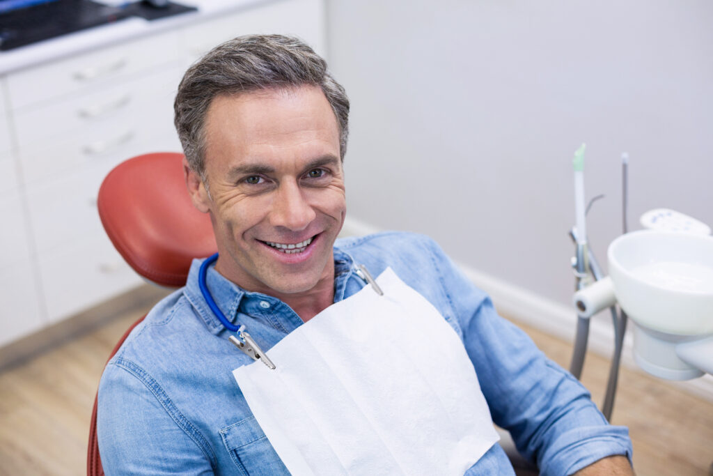 Smiling female patient sitting on dentist chair